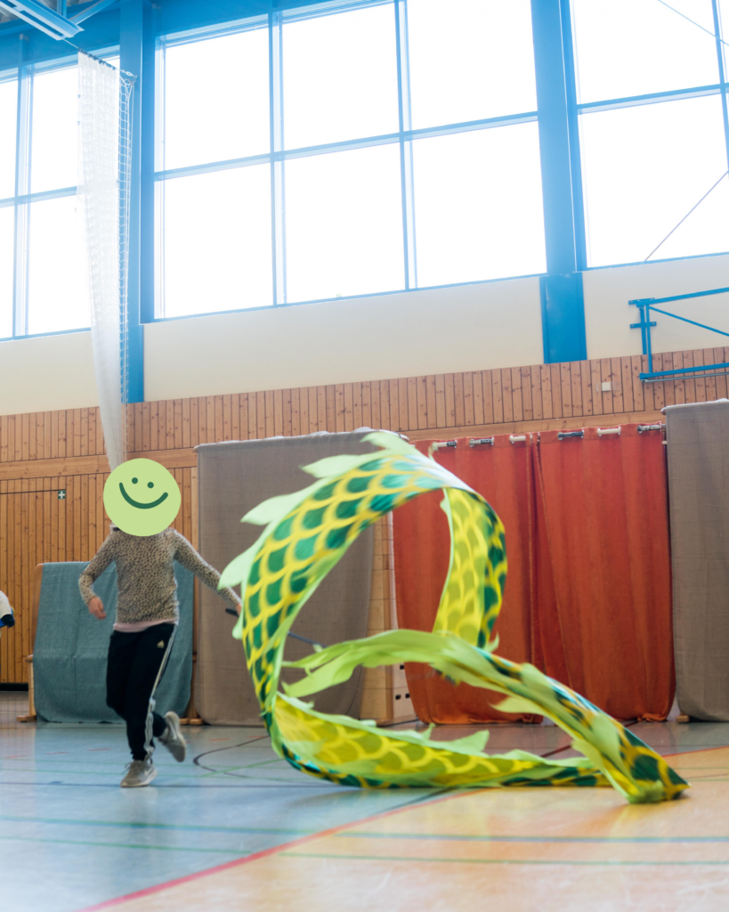 Szene aus einem zirkuspädagogischen Projekt: Ein Kind arbeitet mit einem Zirkusrequisit in einer Sporthalle.